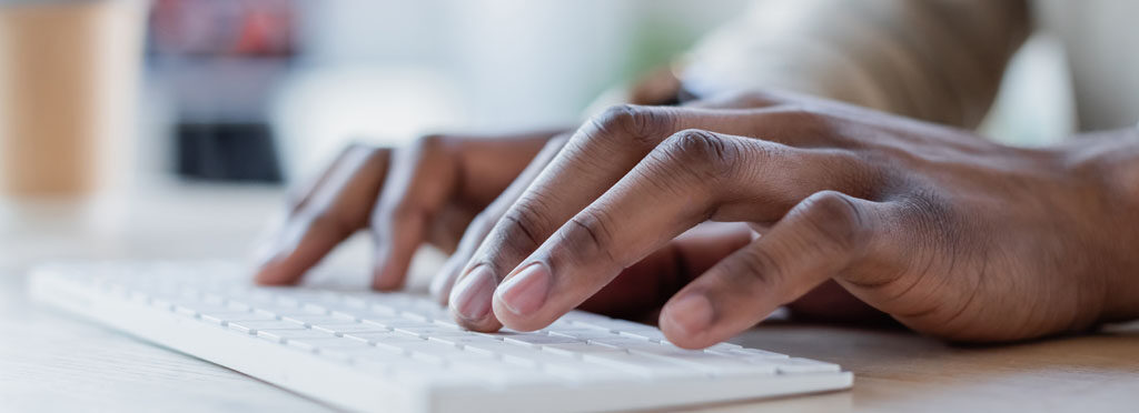 close up view of african american man typing on computer keyboard, banner.